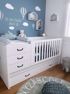 a baby's room with blue walls and white furniture