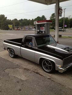 an old pickup truck parked at a gas station