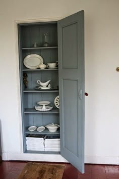 an open cabinet with plates and bowls in it