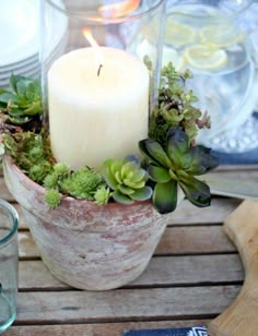 a candle is sitting in a potted planter on a table with plates and utensils