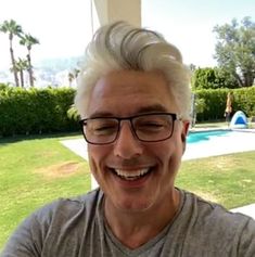 an older man with glasses is smiling for the camera in front of a swimming pool