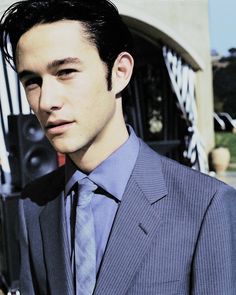 a man wearing a suit and tie standing in front of a building