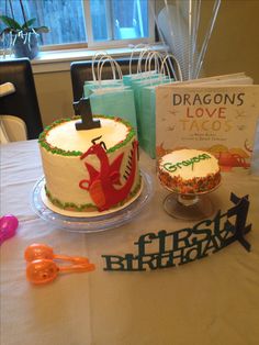 a table topped with two cakes covered in frosting next to a book and scissors