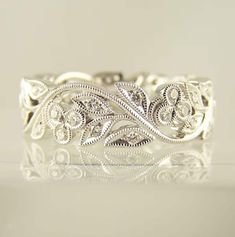 a white gold wedding ring with intricate filigrees and leaves on the band