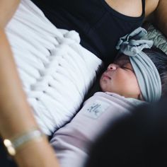 a woman laying on top of a bed next to a baby