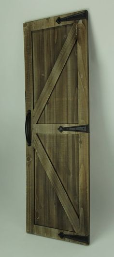 an open wooden door with metal handles on a white wall, hanging from the side