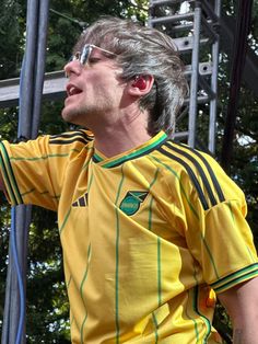 a man in a yellow shirt holding a white frisbee on top of his shoulder