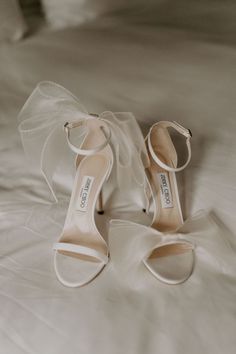 a pair of white high heeled shoes sitting on top of a bed