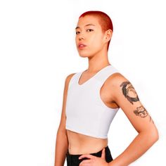 a woman with red hair and tattoos standing in front of a white wall wearing black shorts