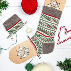 an image of christmas stocking decorations and knitting supplies on a white wooden table with yarn