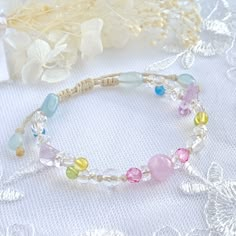 a close up of a bracelet on a table with flowers and leaves in the background