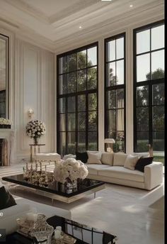 a living room filled with white furniture and large windowed windows next to a fireplace