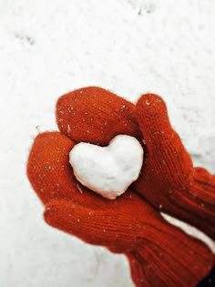 a red glove holding a white heart in the snow