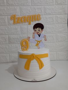 a white cake with yellow ribbon and cartoon figure on top that says azpaque 9