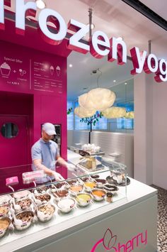 a man standing in front of a frozen yogurt shop with lots of food