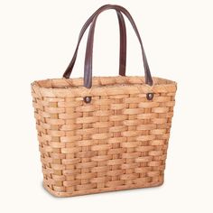 a large woven basket with leather handles on a white background, it is also used as a purse or tote bag