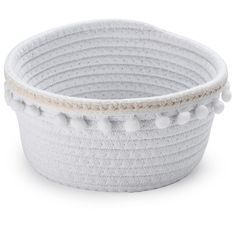 a white basket with pom - poms on the inside and bottom, sitting in front of a white background