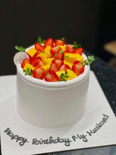 a white bowl filled with fruit sitting on top of a cake covered in frosting