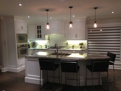 a large kitchen with an island in the middle and three bar stools around it