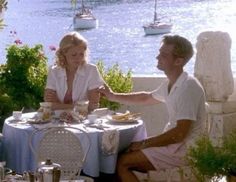 a man and woman sitting at a table with food