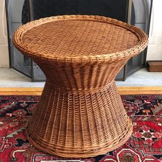 a wicker table sitting on top of a rug in front of a fire place