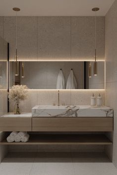 a modern bathroom with marble counter tops and gold fixtures, along with white towels hanging on the wall