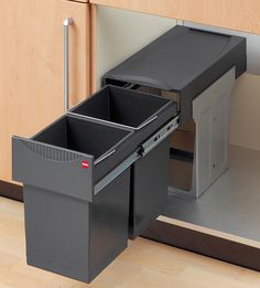 a kitchen cabinet with two bins and a pull out trash can