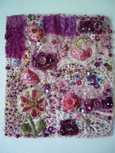 a close up of a piece of art made out of fabric and beads on a white surface