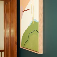 a painting hanging on the wall next to a wooden door with green walls and wood trim