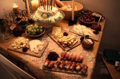 a table topped with lots of different types of cheeses and crackers next to candles