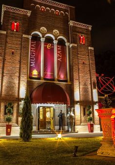 the front entrance of a building lit up at night with red lights and decorations around it