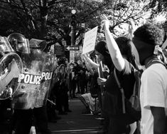 a group of people holding up signs in front of a police car