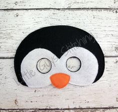 a black and white penguin mask with two eyes on it's face, sitting on a wooden surface