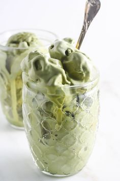 two glasses filled with green ice cream on top of a table next to each other