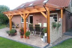 a patio covered in plants next to a brick building with an attached pergolan