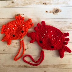 two crocheted red and orange hats sitting on top of a white wooden floor