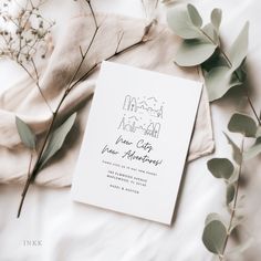 the wedding stationery is laid out on a bed with flowers and greenery around it