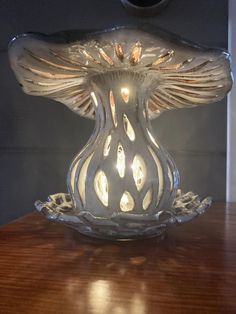 a glass candle holder sitting on top of a wooden table next to a mirror wall