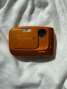 an orange cell phone sitting on top of a white blanket