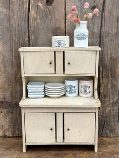 an old dresser with plates and vases on it