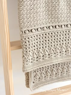 a crocheted blanket is hanging on a wooden chair next to a white wall