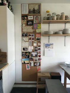 a kitchen wall with pictures and magnets on the back side, hanging from wooden shelves