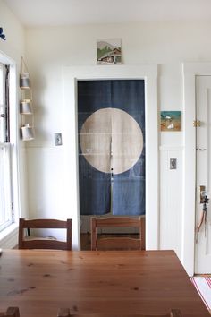 a wooden table sitting in front of a doorway next to a white door with an oval painting on it