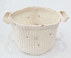 a white basket sitting on top of a bed