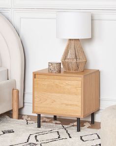 a nightstand with a lamp on it next to a couch