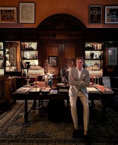 a man sitting at a desk in front of a bookcase with books on it