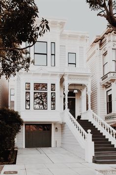 a large white house with stairs leading up to the front door and two story windows