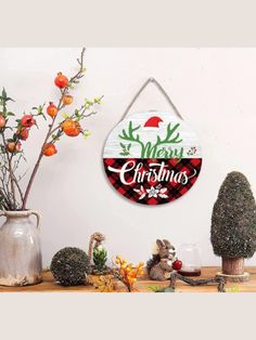 a merry christmas sign hanging from the side of a wall next to potted plants