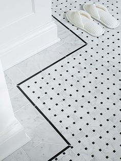 a pair of white slippers sitting on top of a bathroom floor next to a toilet