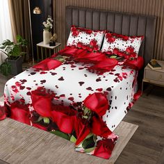 a bed with red roses and hearts on the cover is in a room that has wooden floors